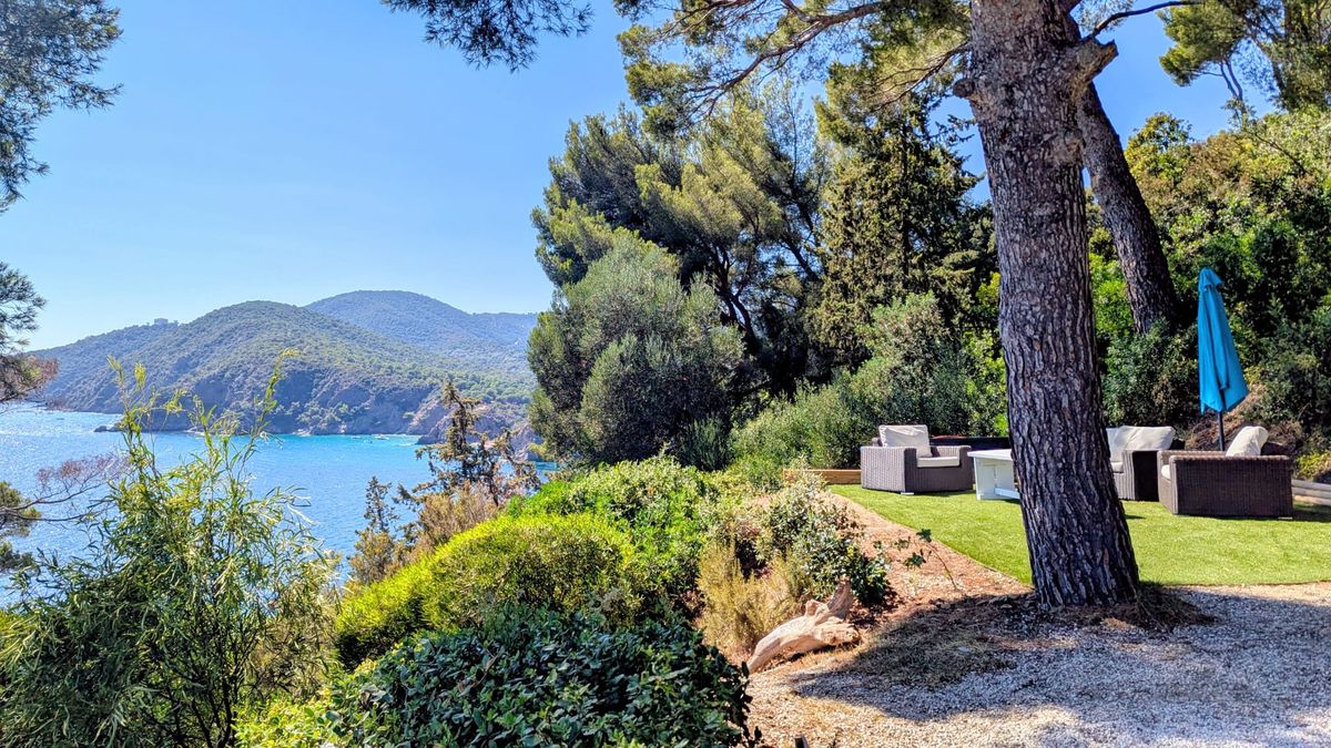 Jardin d’une villa gérée à Cavalaire-sur-Mer, salon sous les pins face à la mer et aux collines